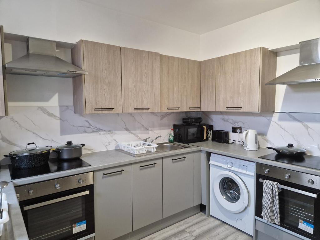 a kitchen with wooden cabinets and a washer and dryer at P Williams Plumstead in Plumstead