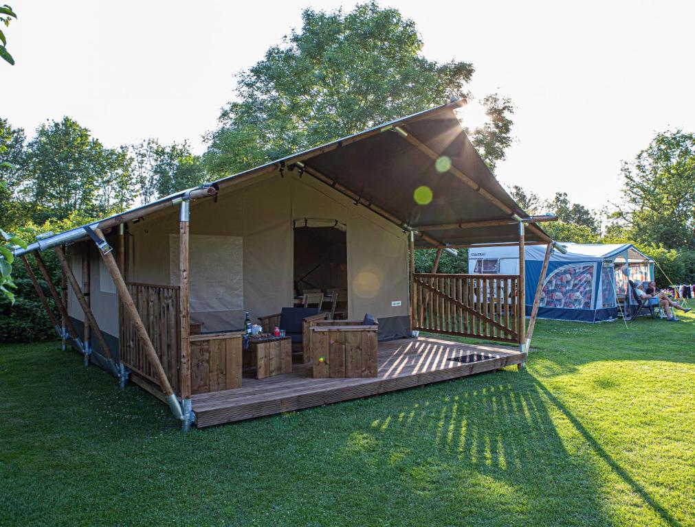 a large tent with a deck on the grass at Safaritent Suikerpeer in Ruinerwold