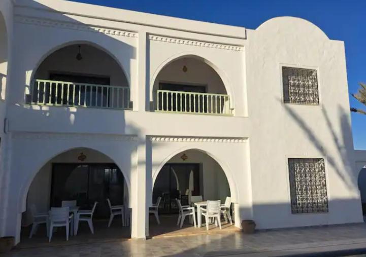 ein weißes Gebäude mit Tischen und Stühlen in der Unterkunft villa izabelles in Djerba