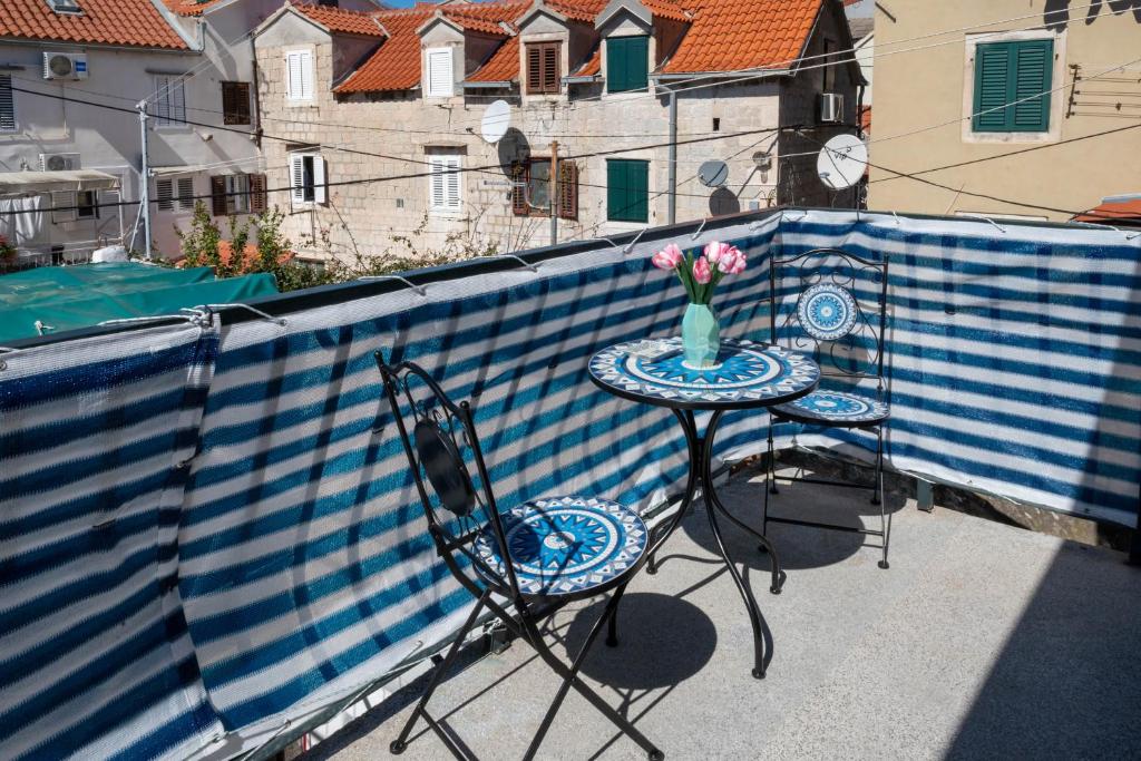 a table and chairs on a balcony with a vase of flowers at Guest house Ivona in Split
