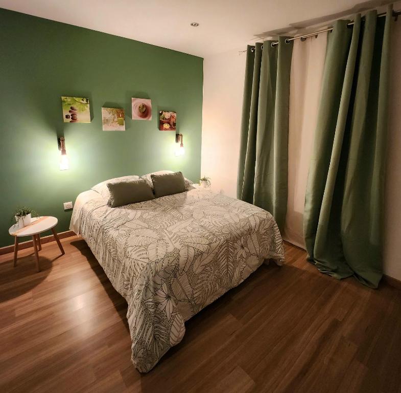 a bedroom with a bed and a green wall at Au Doux Refuge in Le Lambert