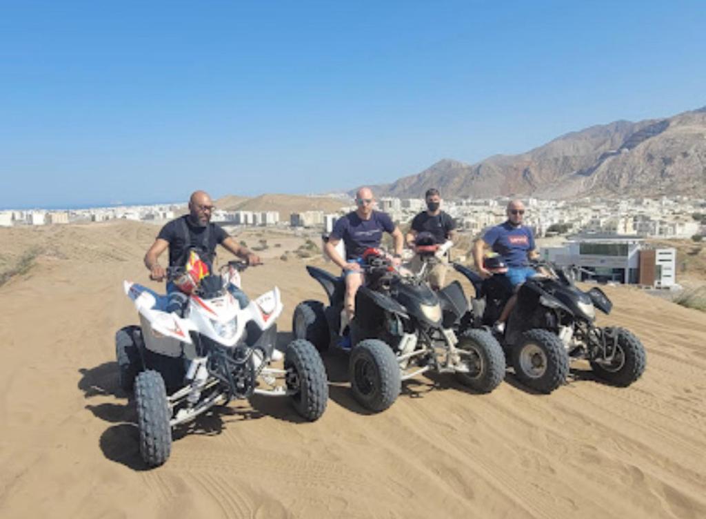 un grupo de hombres sentados en la arena en Muscat sand apartments, en Mascate