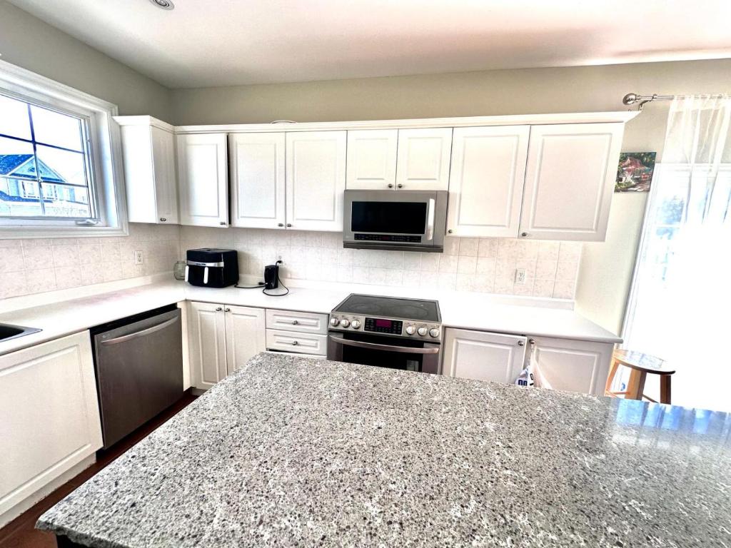 a kitchen with white cabinets and a granite counter top at Home with Nance in Oshawa