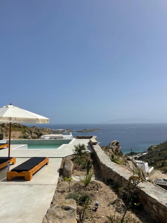 a swimming pool with an umbrella and the ocean at Apostolis Windmill in Psarou