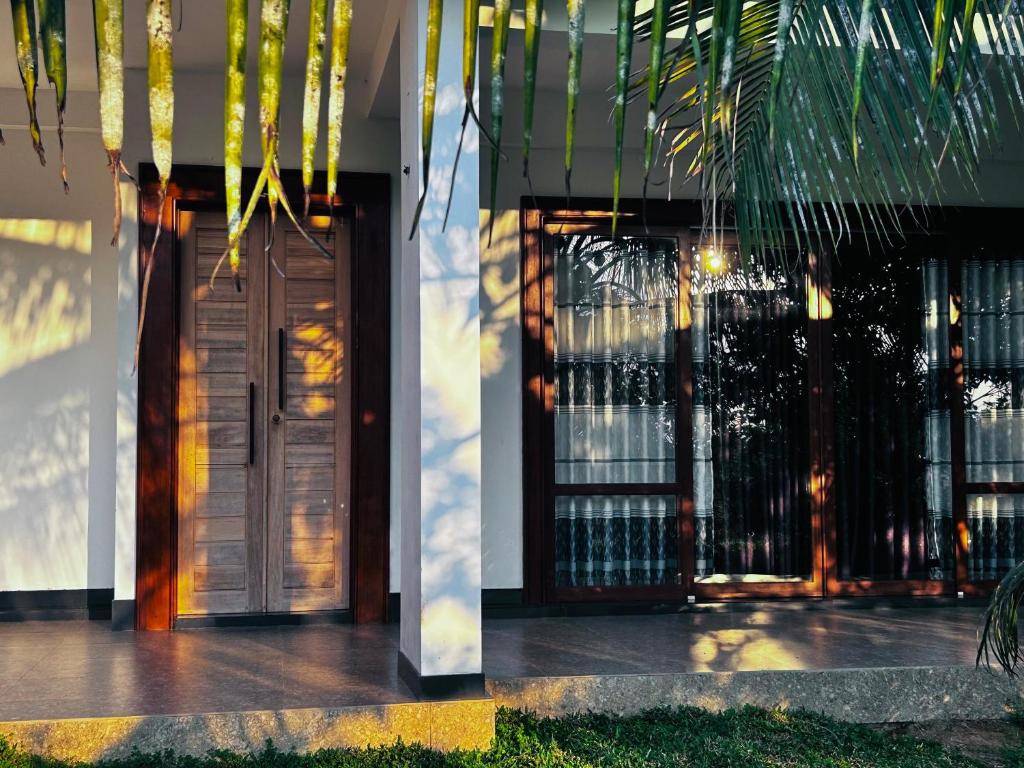 a building with a door and a palm tree at Windy Villa in Polonnaruwa