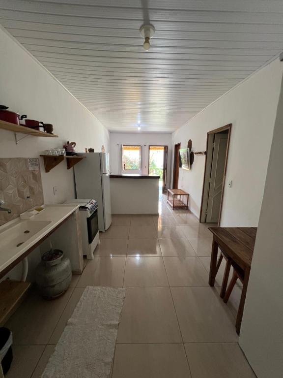 a large kitchen with white appliances and a table at Vila Uryah in Caraíva