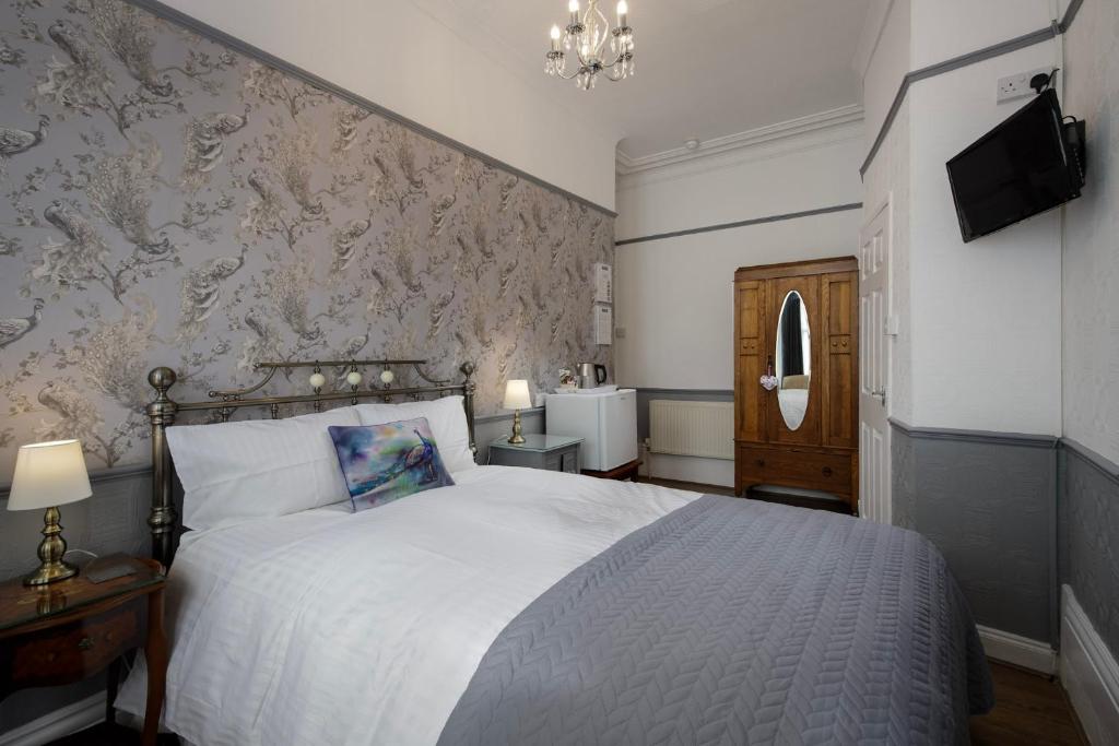 a bedroom with a white bed and a wall with wallpaper at The Wescoe Guesthouse in Blackpool