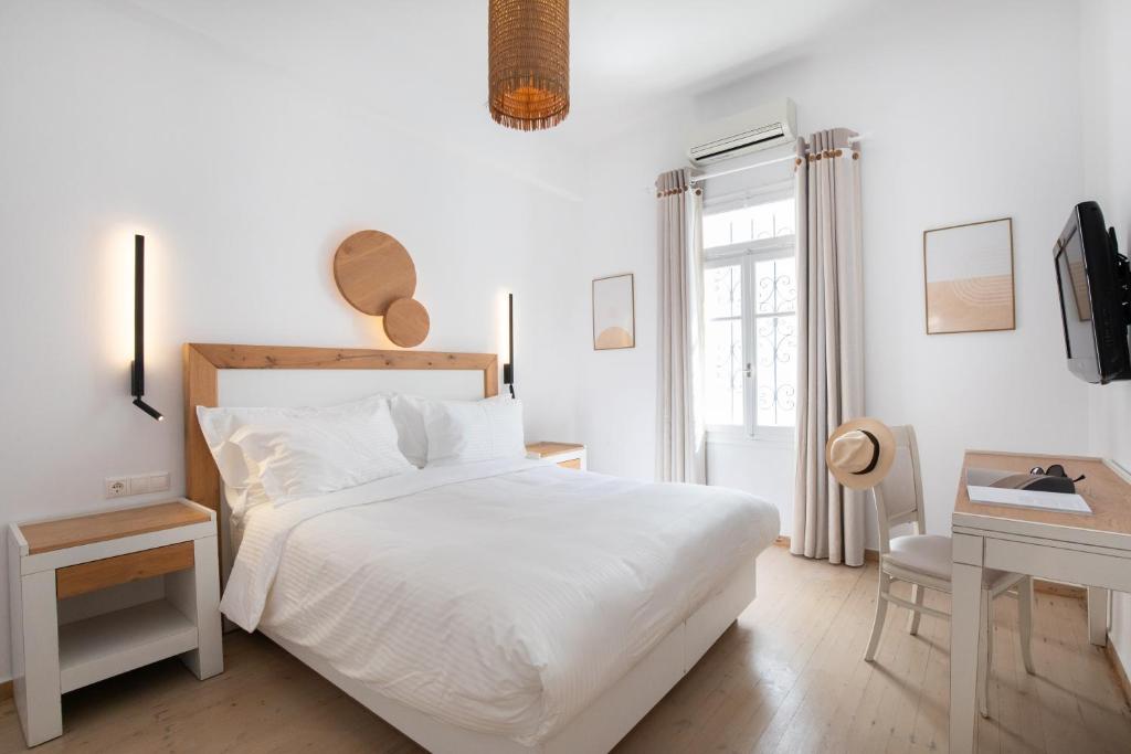 a white bedroom with a white bed and a desk at Spitarona Town House - Largest VIlla in the Center in Mýkonos City