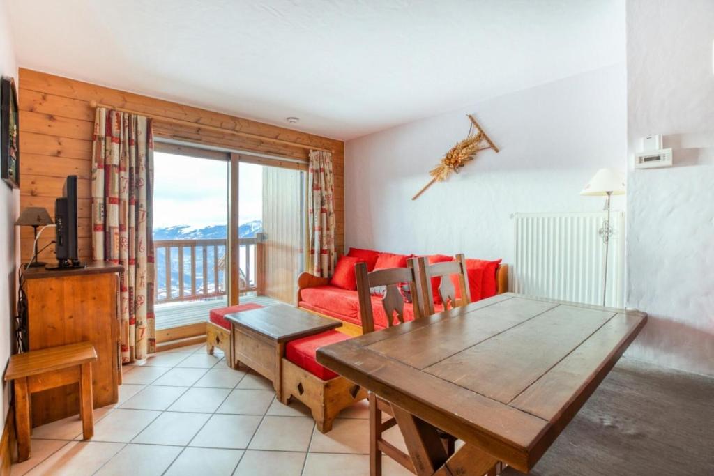 un salon avec un canapé rouge et une table dans l'établissement Résidence Les Alpages de Chantel - maeva Home - Appartement 3 Pièces 6 Personnes - Sélection MAE-1538, à Bourg-Saint-Maurice
