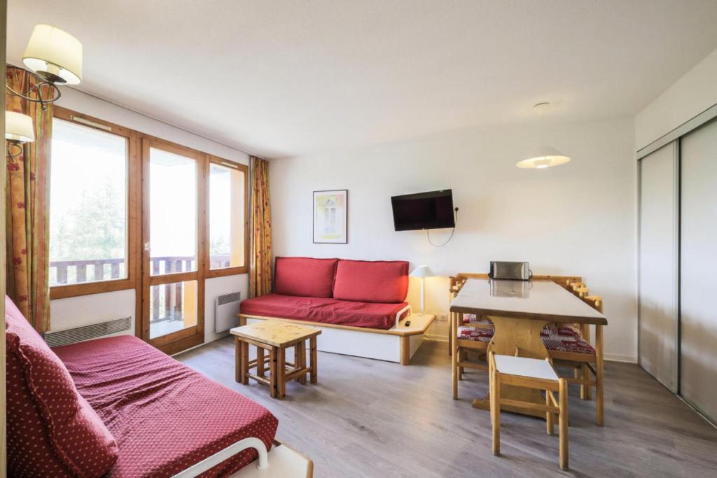 un salon avec un canapé rouge et une table dans l'établissement Résidence Le Hameau du Sauget - maeva Home - 3 Pièces 6 Personnes Sélection MAE-1979, à La Plagne Tarentaise