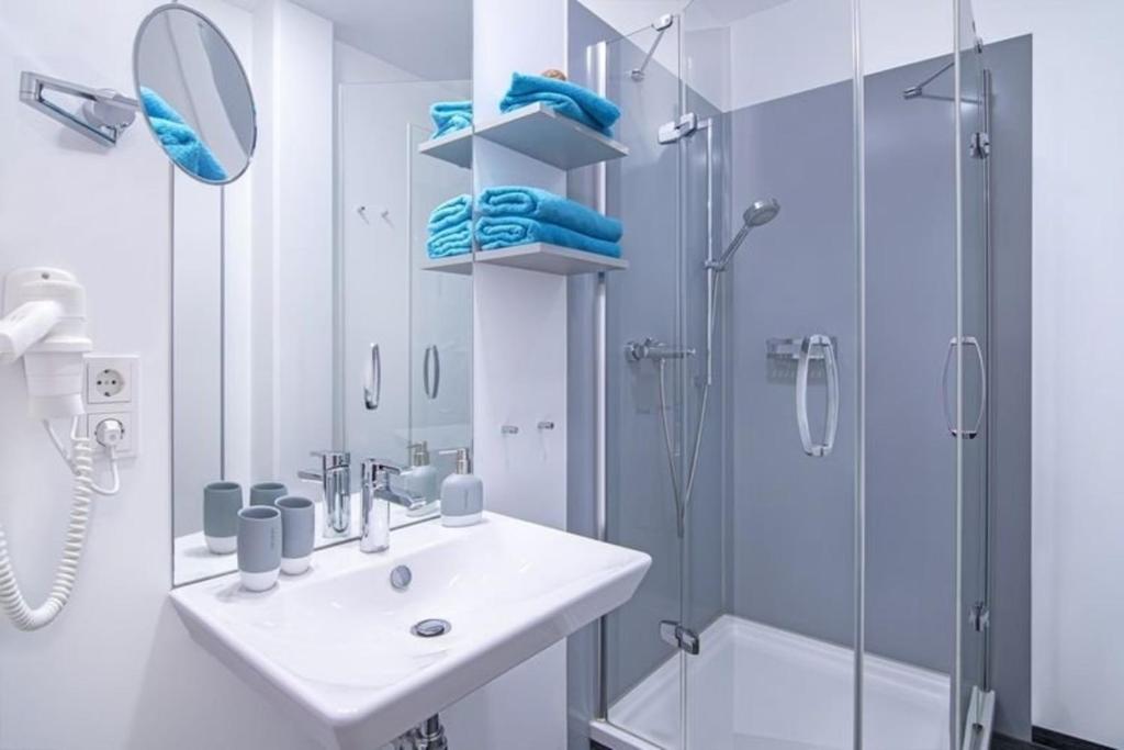 ein weißes Bad mit einem Waschbecken und einer Dusche in der Unterkunft Doppelzimmer im Strandhaus 2 in Elsterheide