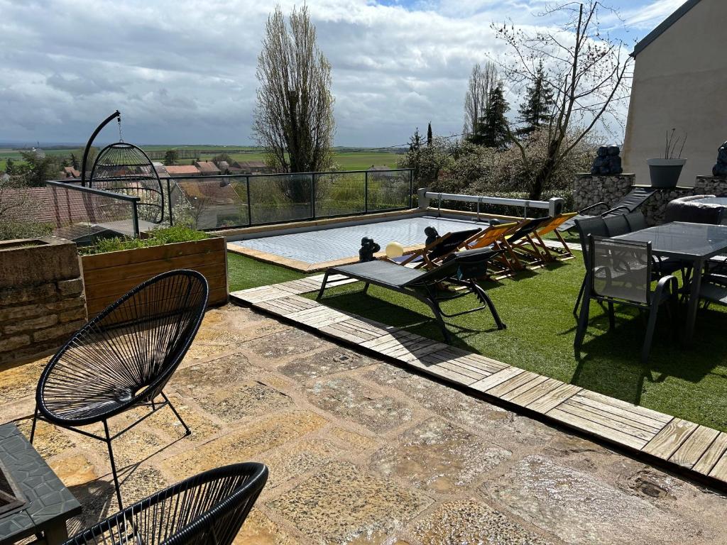 un patio con mesa, sillas y piscina en La maison du chêne, en Chaignay