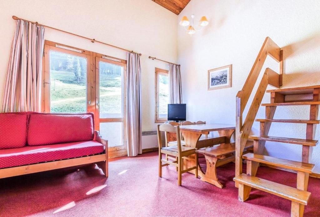 uma sala de estar com um sofá vermelho e uma escada em Quartier Crève Cœur - maeva Home - Duplex 3 Pièces 8 Personnes Confort 03 em Valmorel