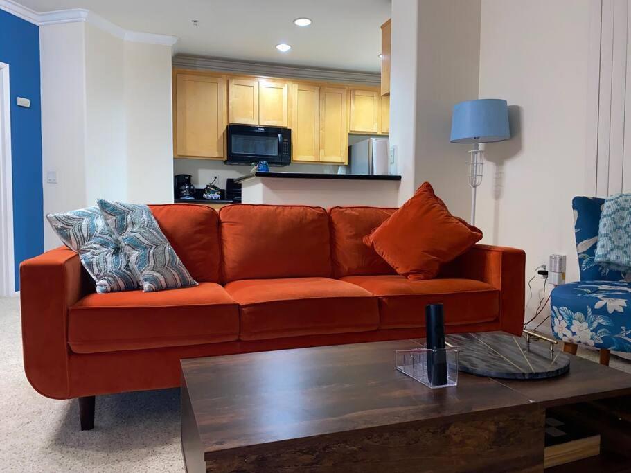 een oranje bank in een woonkamer met een tafel bij Orsini Luxury Retreat: 2BR/2BA in Los Angeles