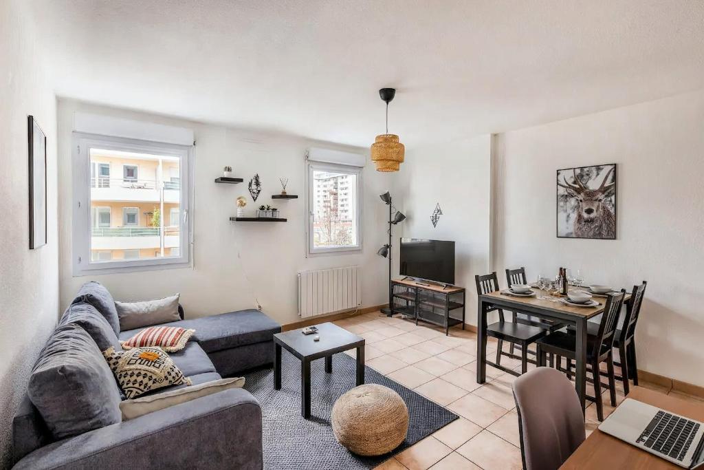 ein Wohnzimmer mit einem Sofa und einem Tisch in der Unterkunft Cosy appartement - Parking Privé Gratuit in Chambéry
