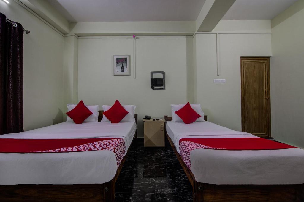 Duas camas num quarto com almofadas vermelhas em OYO Flagship 14426 V Knot Residency em Garacherāma