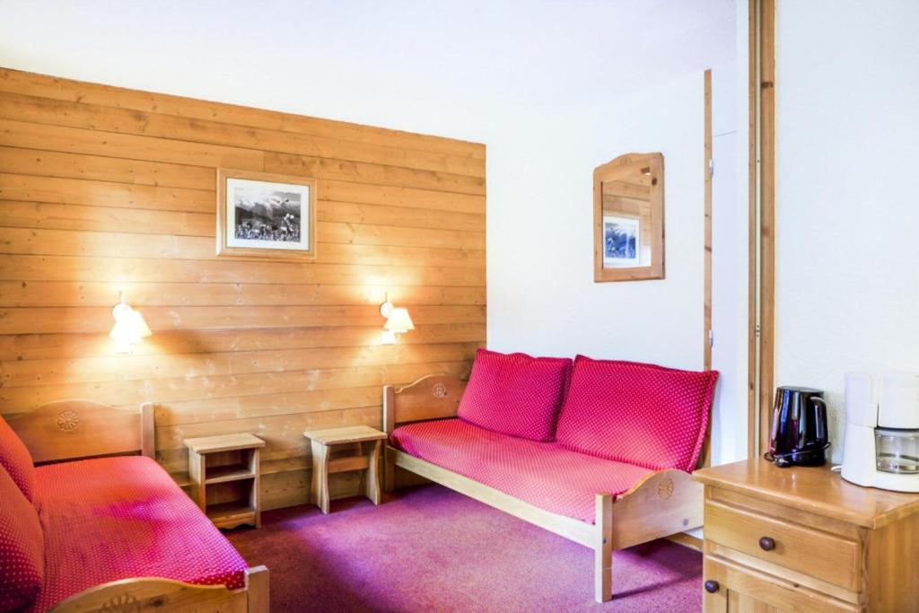 Cette chambre dispose d'un canapé rouge et d'un mur en bois. dans l'établissement Quartier La Forêt - maeva Home - Studio 4 Personnes Confort MAE-4163, à Valmorel