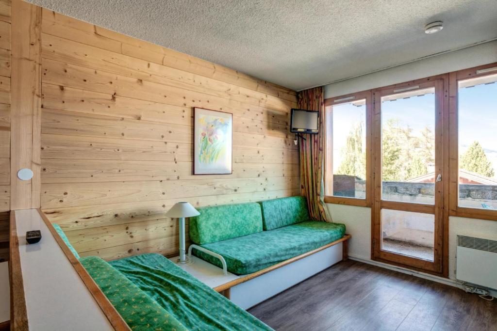 Cette chambre dispose d'un canapé vert et d'une fenêtre. dans l'établissement Résidence Le Hameau du Sauget - maeva Home - 2 Pièces 4 Personnes Confort MAE-4185, à La Plagne Tarentaise