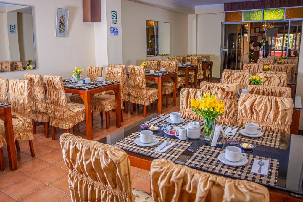 a dining room with tables and chairs and flowers at Hotel Independencia in Huaraz