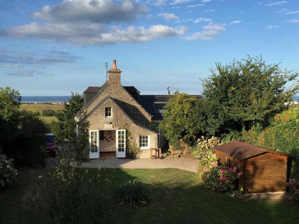 une ancienne maison en pierre avec un jardin en face de celle-ci dans l'établissement Maison de charme vue sur mer pour 6 pers, à Quinéville