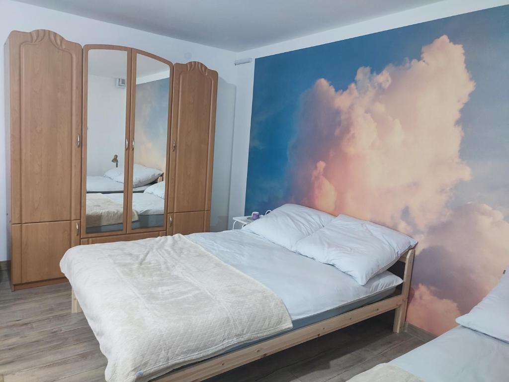 a bedroom with a cloud mural on the wall at Pod Lasem in Nowe Miasto Lubawskie