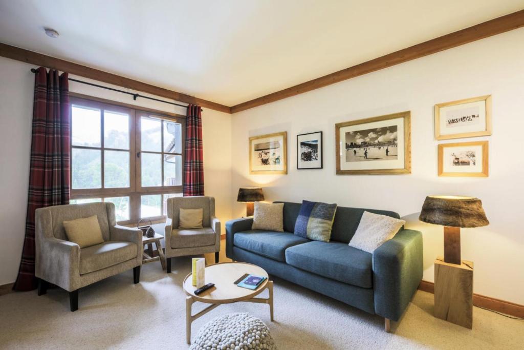 un salon avec un canapé bleu et deux chaises dans l'établissement Résidence Les Arcs 1950 Le Village - maeva Home - 3 Pièces 6 Personnes Exclusive MAE-6150, à Bourg-Saint-Maurice