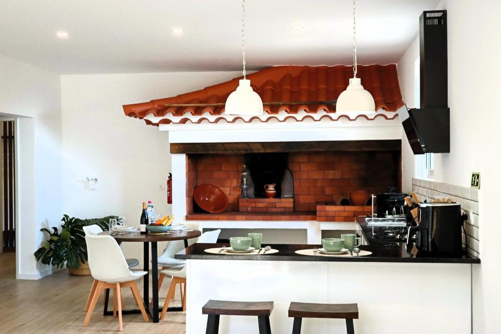 uma cozinha com lareira, mesa e cadeiras em A Casa Da Mãe em São Vicente