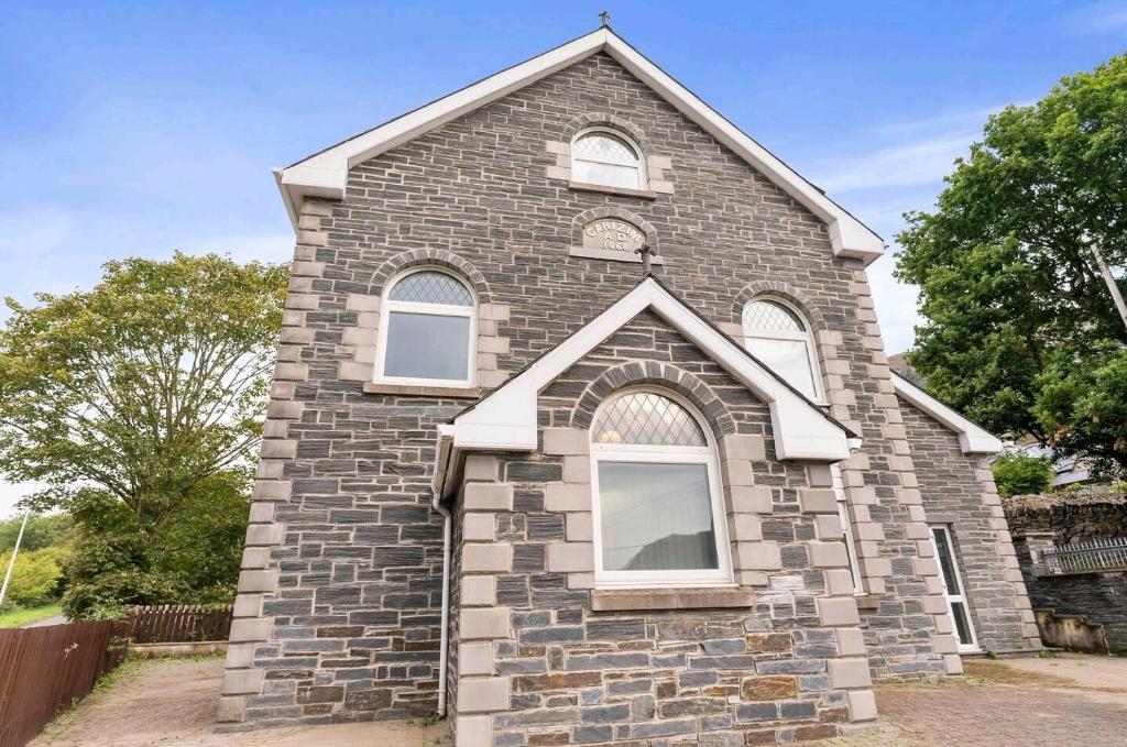 a small brick church with three windows on it at Spacious & bright home with parking, ensuite, view in Tremadoc