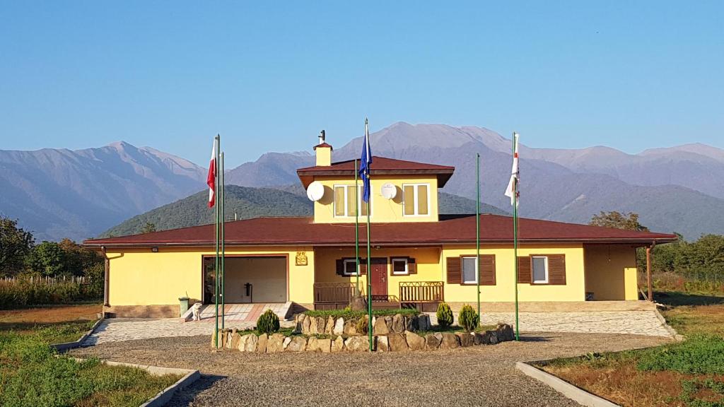 a yellow house with two flags in front of it at Rancho Laila in Shilda