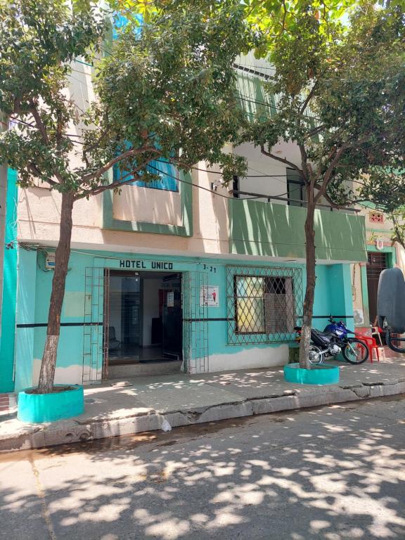 Hotel Unico City في سانتا مارتا: مبنى ازرق امامه شجرتين