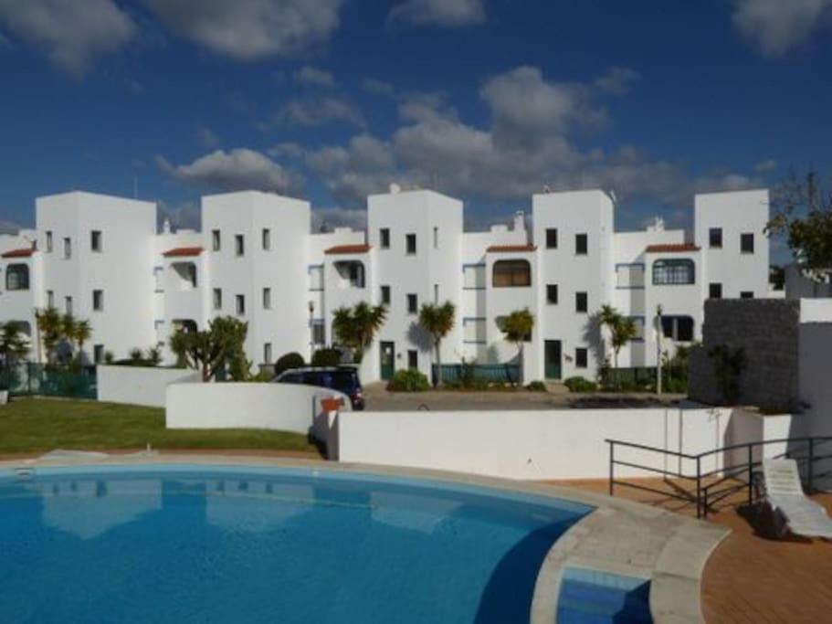 a resort with a swimming pool in front of a building at Apartamento encantador a 100m da praia in Carvoeiro