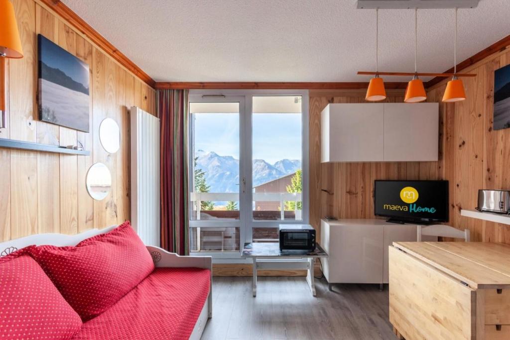 un salon avec un canapé rouge et une table dans l'établissement Résidence Les Horizons d'Huez - maeva Home - Appartement 2 Pièces 5 Personnes - Sélection MAE-2698, à Huez