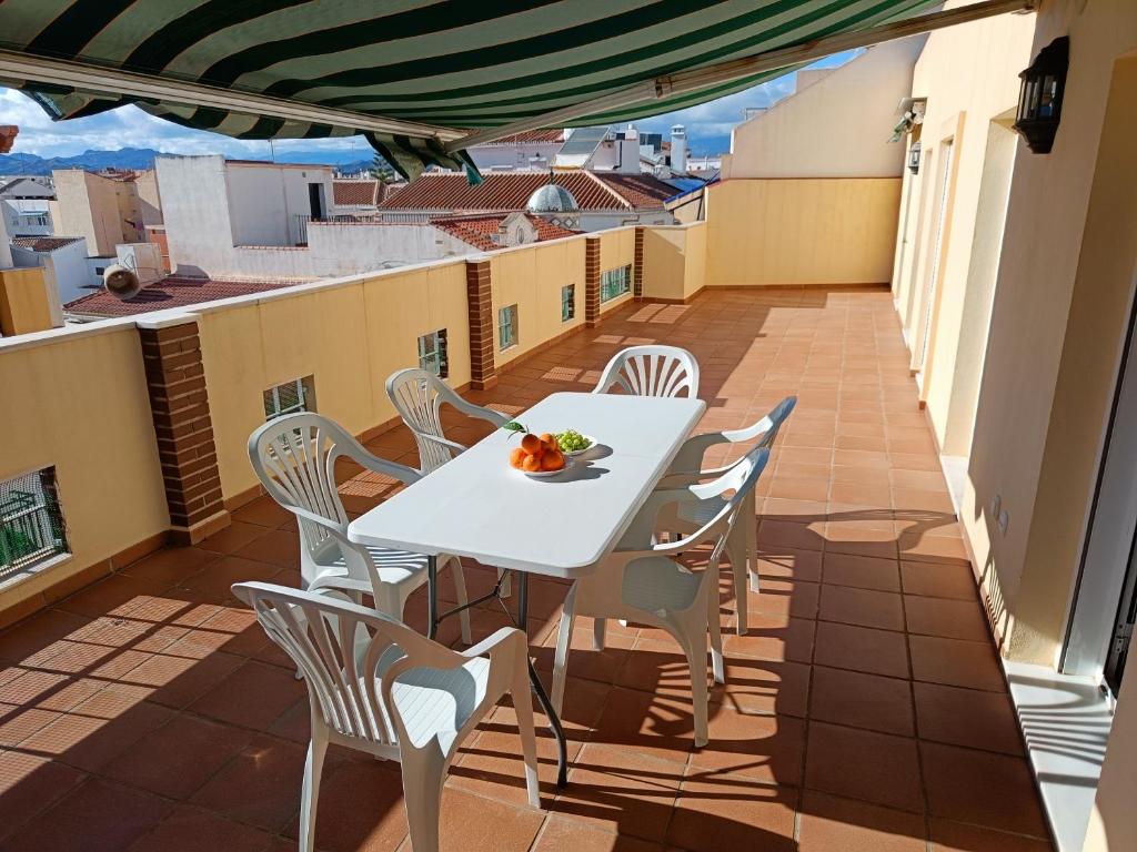 - Balcón con mesa blanca y sillas en Los Maestros: ático en el centro de Vélez-Málaga, en Vélez-Málaga