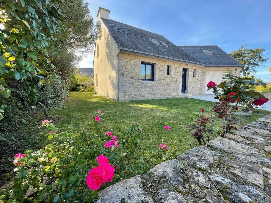 une maison en pierre avec des fleurs roses devant elle dans l'établissement Maison familiale Cosy plage à pied, à Arzon
