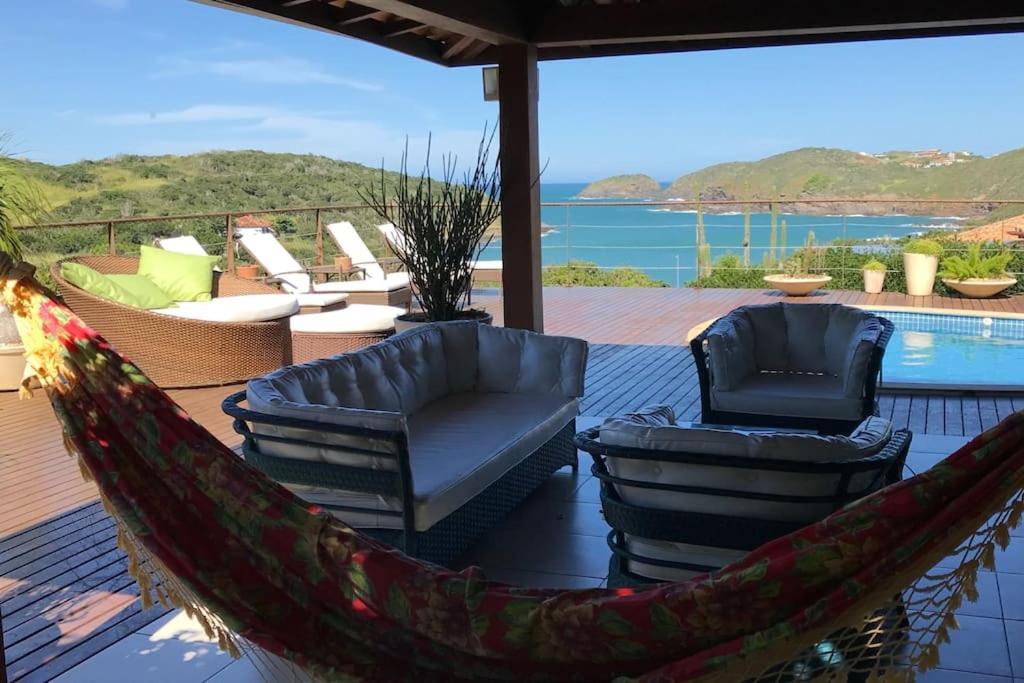 a hammock on a deck with chairs and a pool at Paraíso Buziano 1 in Búzios