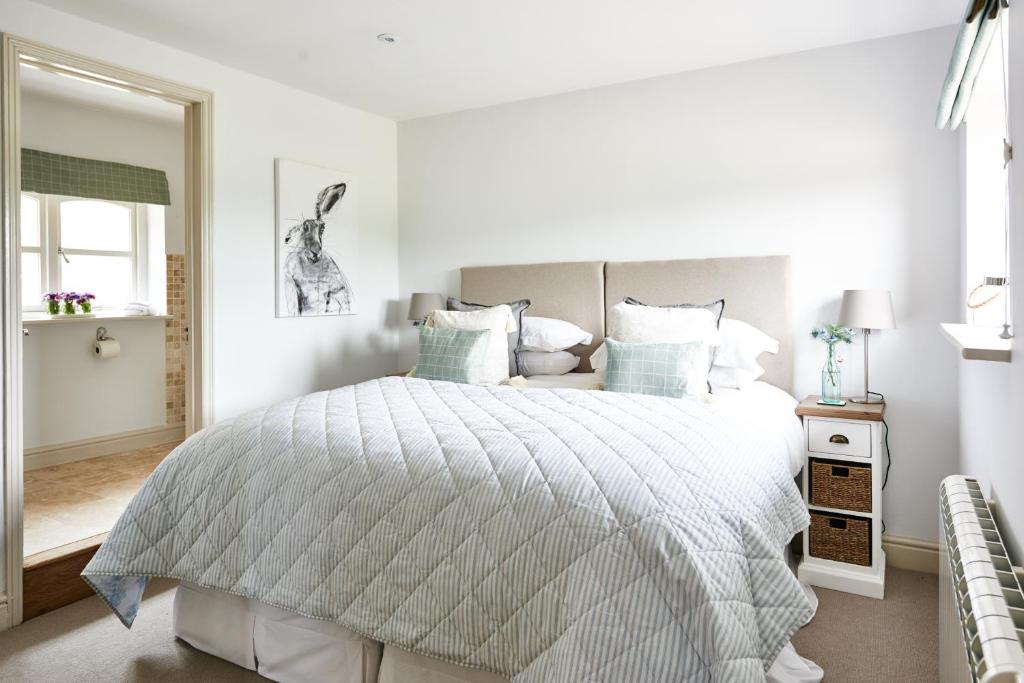 a white bedroom with a large bed with blue pillows at Cromhall Farm in Chippenham