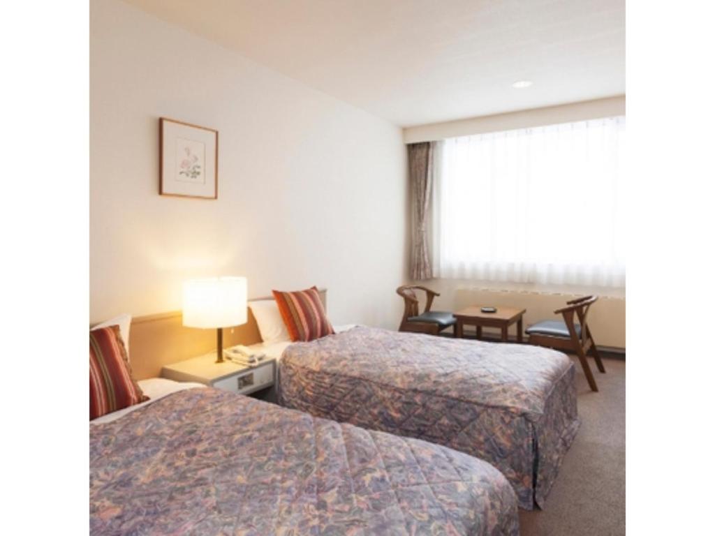 ein Hotelzimmer mit 2 Betten und einem Tisch in der Unterkunft Mount View Hotel - Vacation STAY 40096v in Kamikawa