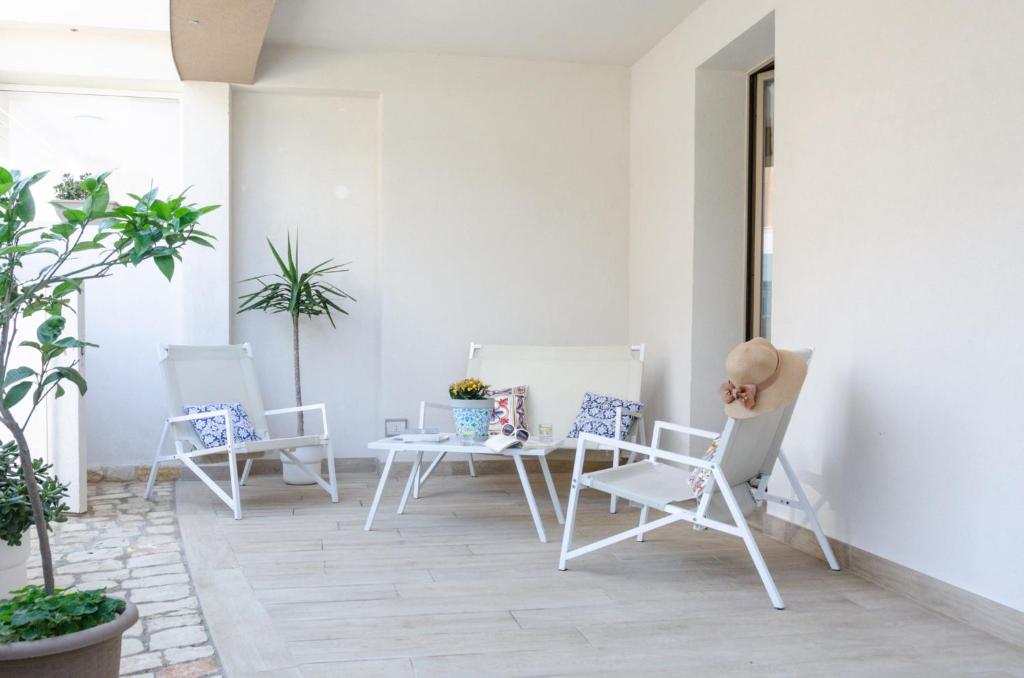 a patio with white chairs and a table at Mediterraneo ORO in Marzamemi