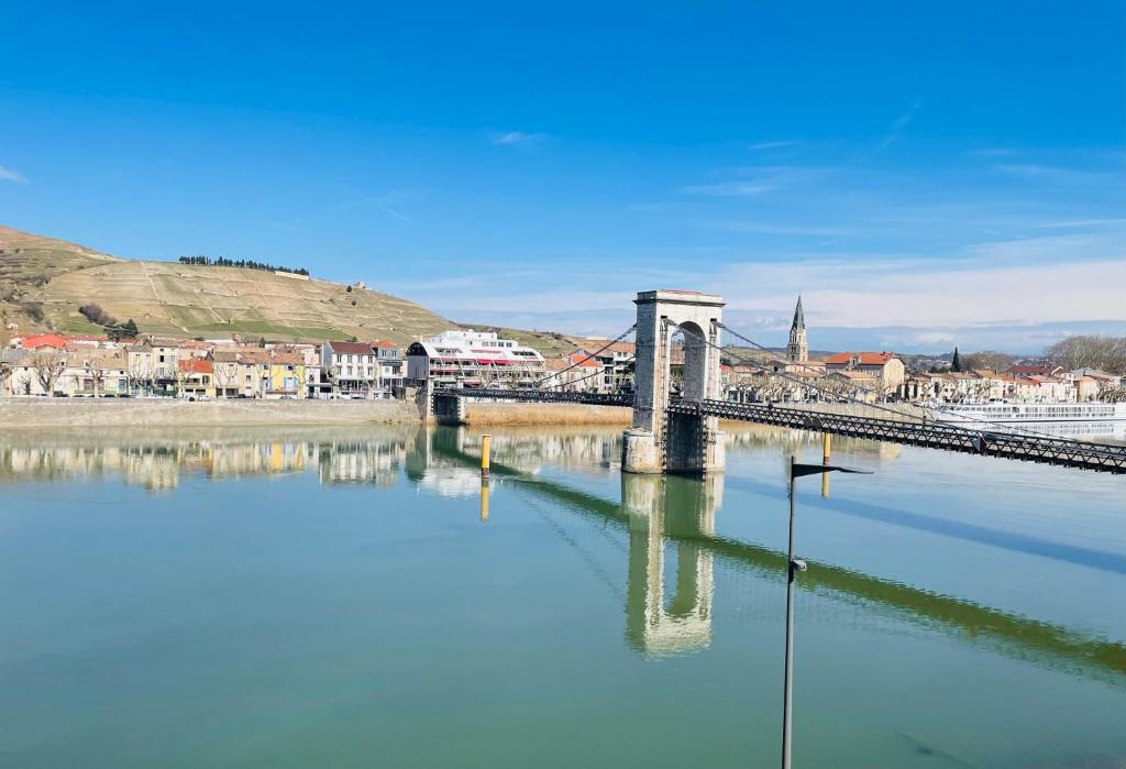 un puente sobre un río con una ciudad al fondo en Studio de 42m2, vue imprenable, en Tournon-sur-Rhône