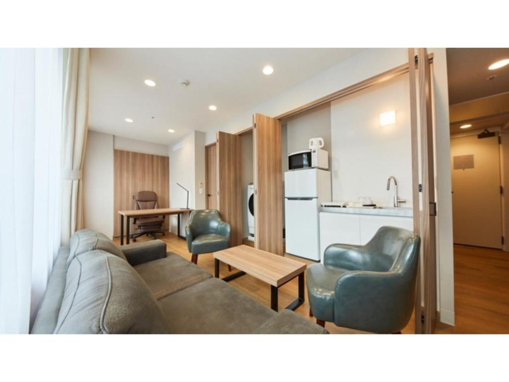 a living room with a couch and chairs and a kitchen at Rembrandt Hotel Atsugi - Vacation STAY 41677v in Atsugi