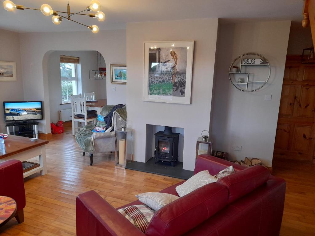 uma sala de estar com um sofá vermelho e uma lareira em House Overlooking Ballinskelligs Bay em Waterville