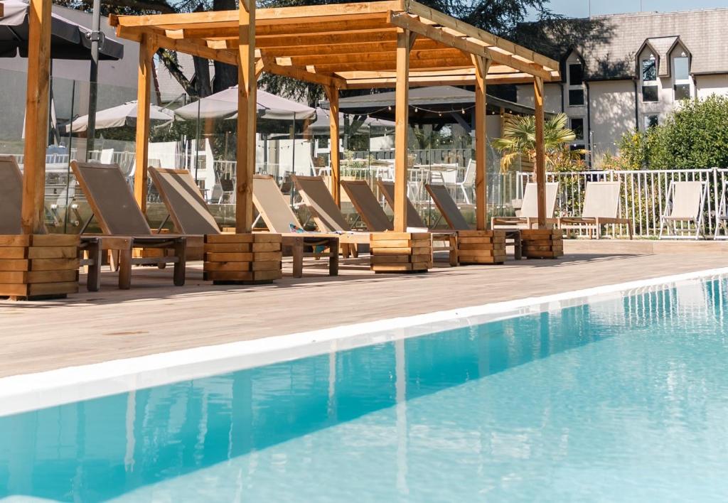 a group of lounge chairs next to a swimming pool at Mercure Parc du Coudray - Barbizon in Le Coudray-Montceaux