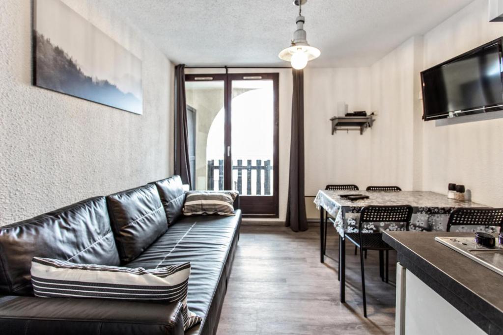 a living room with a leather couch and a table at Studio 4 personnes avec terrasse vue montagne à Vars 103282 in Vars