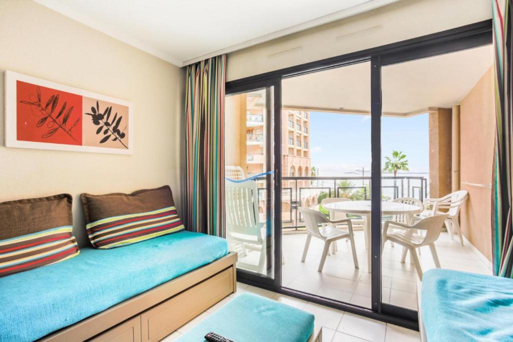 Cette chambre dispose d'un canapé et d'un balcon avec une table. dans l'établissement Résidence Cannes Verrerie - maeva Home - Appartement 3 Pièces 6 Personnes - Selection MAE-0305, à Cannes