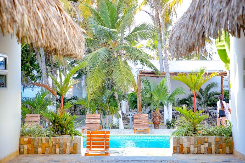 a resort with a pool and palm trees and chairs at Hotel Palma Grande by Stanza in Coveñas