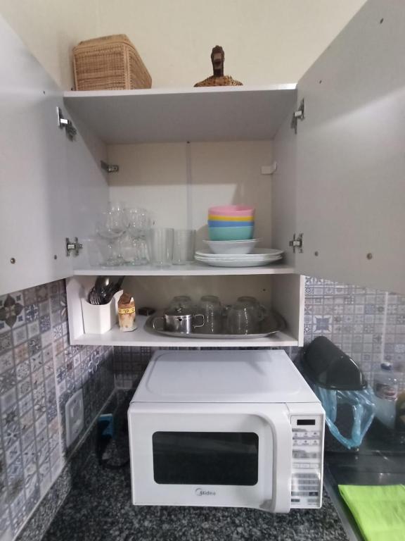 a microwave oven in a kitchen with some dishes at Chalés Pássaros do Cerrado in Cavalcante