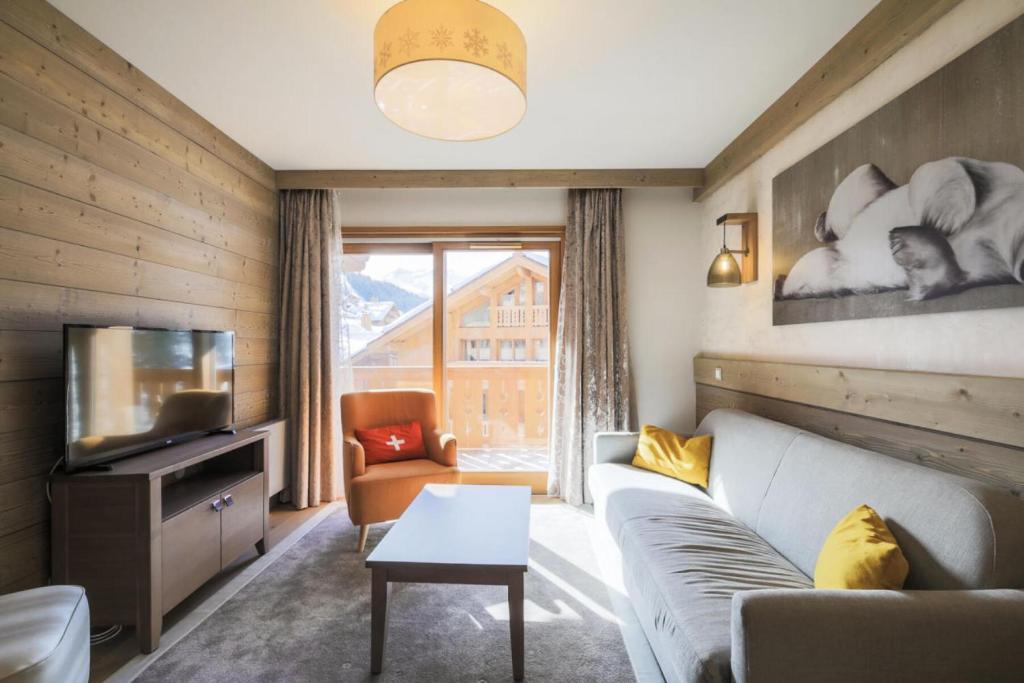ein Wohnzimmer mit einem Sofa und einem TV in der Unterkunft Résidence Premium L'Hévana - maeva Home - Appartement 3 pièces 6 personnes 94 in Les Allues