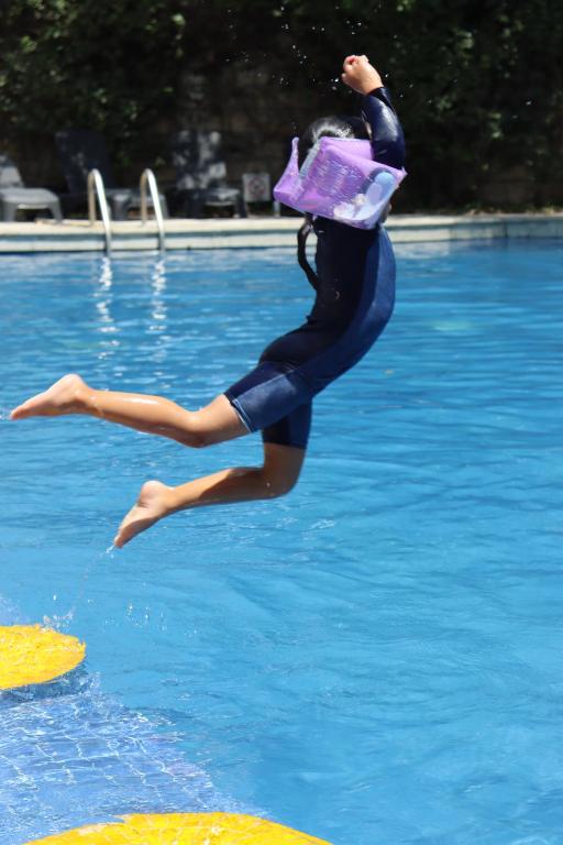 a woman is jumping into a swimming pool at Novotel Monterrey Valle in Monterrey