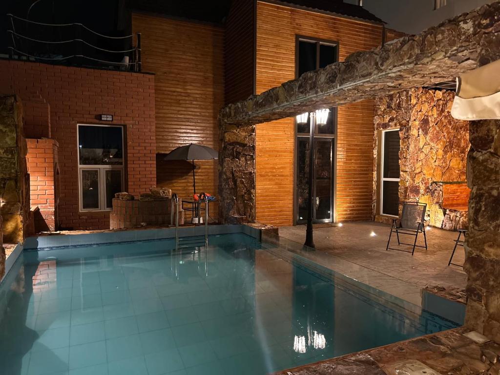 a swimming pool in a house with a stone wall at كوخ الشاطئ جمال الحاضر والطبيعة in Jazan