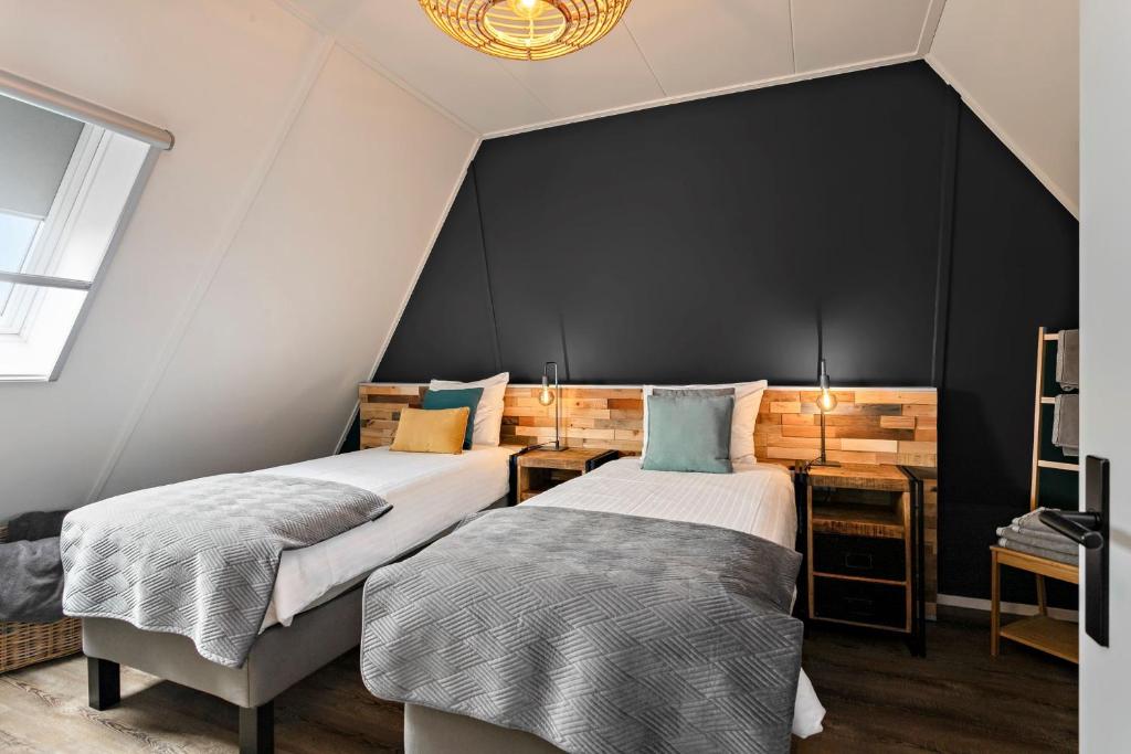 2 łóżka w pokoju z czarną ścianą w obiekcie Prachtige vakantievilla Burdaard w mieście Birdaard